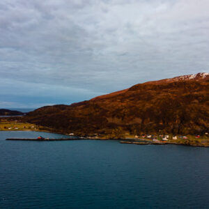 Aerial view of a village along the shore below a russet hillside, Seglvik, Troms, Norway