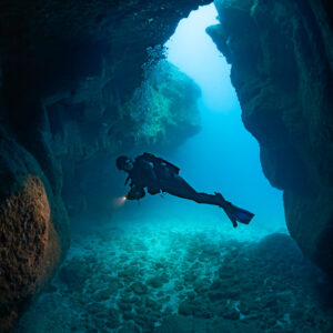Plongeuse traversant l’ouverture d’une grotte, cadrage vertical, Flic-en-Flac, île Maurice