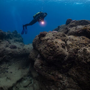 Plongeuse avec phare au-dessus d’un gros rocher, cadrage vertical, Flic-en-Flac, île Maurice