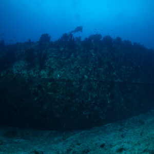 Wreck hull lying on the bottom with a distant diver, Maldives