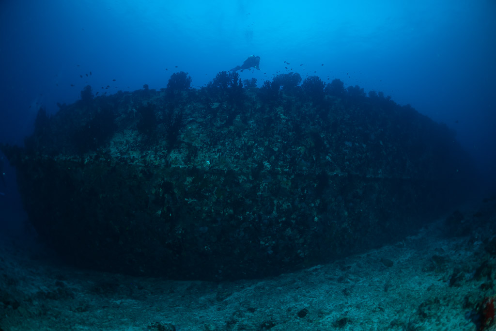 Wreck hull lying on the bottom with a distant diver, Maldives