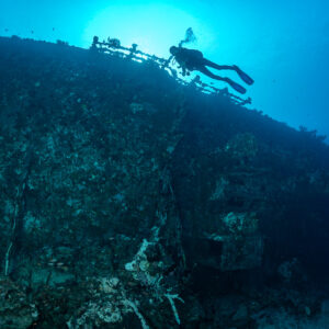 Diver swimming along the deck railing of a sunken ship, Maldives