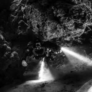 Rebreather diver with torches in the cave, black and white, Zabargad, Red Sea, Egypt