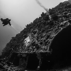 Rebreather diver above the overturned hull of the Levanzo wreck, black and white, Red Sea, Egypt