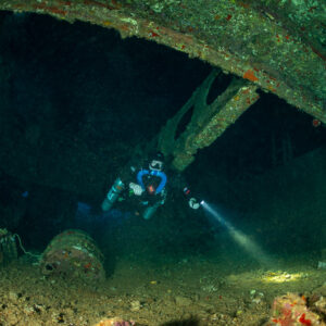 Rebreather diver exploring the hold of the Levanzo wreck with torch, Red Sea, Egypt