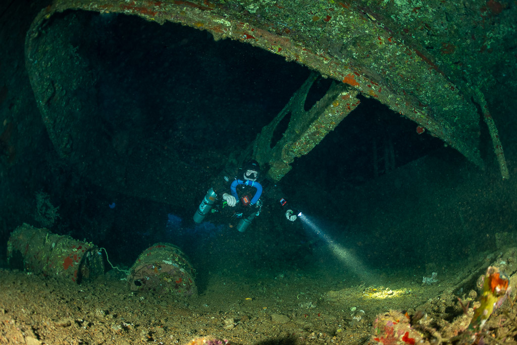 Rebreather diver exploring the hold of the Levanzo wreck with torch, Red Sea, Egypt