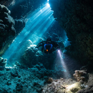 Rebreather diver in a cave crossed by sunbeams, Gota Jeny, Red Sea, Egypt