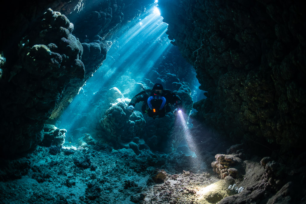 Rebreather diver in a cave crossed by sunbeams, Gota Jeny, Red Sea, Egypt