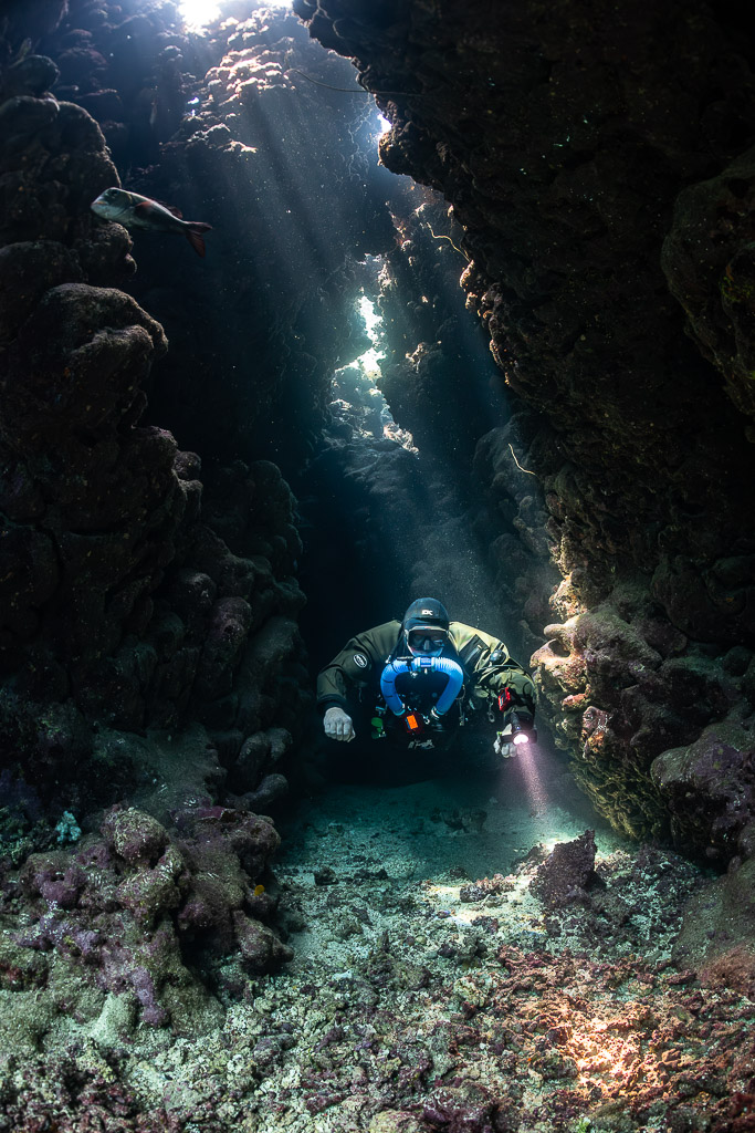 Rebreather diver in a narrow cave corridor with light from above, Gota Jeny, Red Sea, Egypt