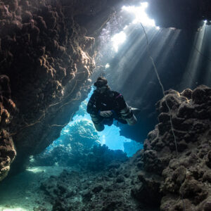 Rebreather diver passing a cave window with guideline, Gota Jeny, Red Sea, Egypt