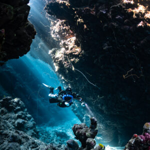 Rebreather diver in a cave gallery with a sunlit window, Gota Jeny, Red Sea, Egypt