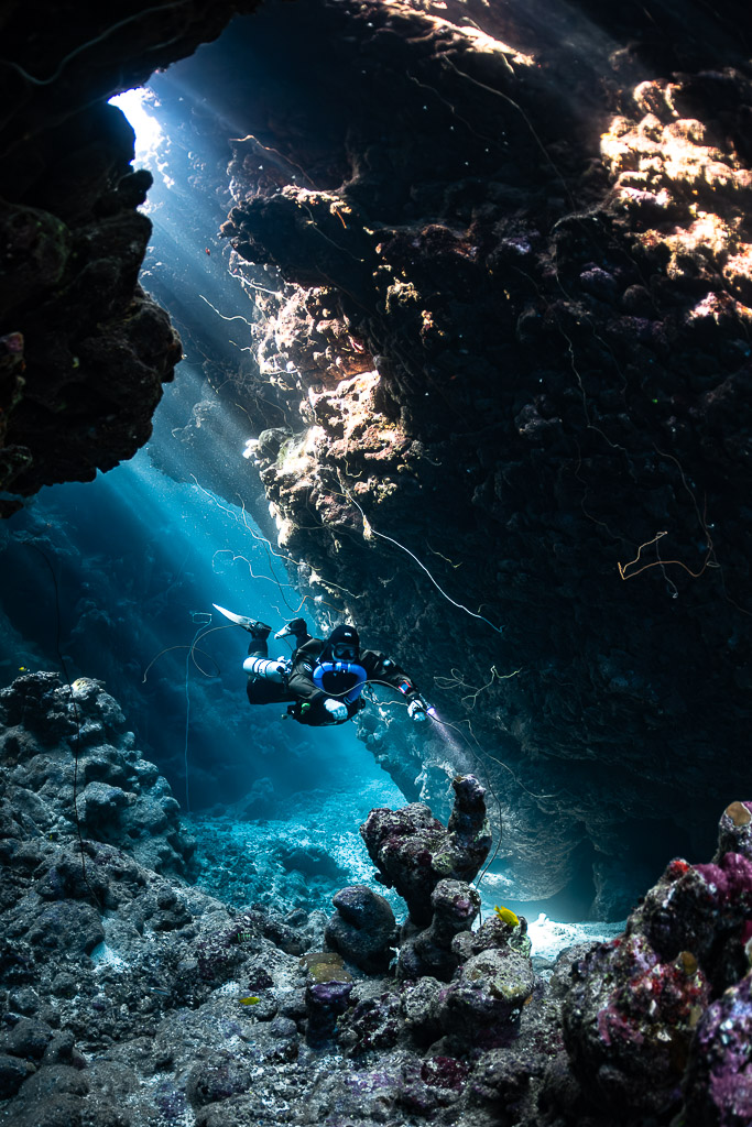 Rebreather diver in a cave gallery with a sunlit window, Gota Jeny, Red Sea, Egypt