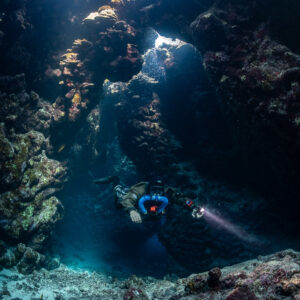 Rebreather diver below a skylight in the cave, Saint John's Cave, Red Sea, Egypt