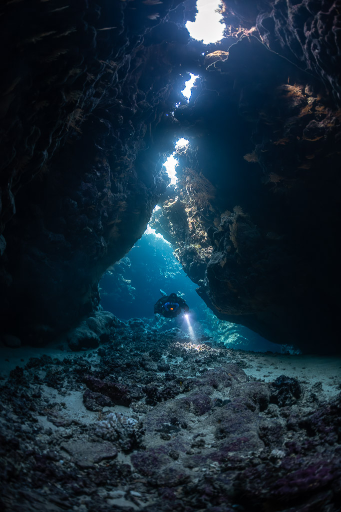 Distant rebreather diver below a chain of skylights, Saint John's Cave, Red Sea, Egypt