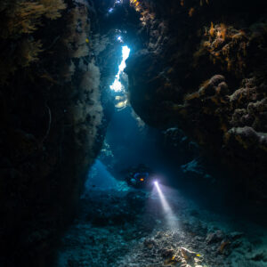 Rebreather diver in a tall cave fissure with skylights, Saint John's Cave, Red Sea, Egypt