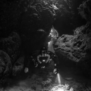 Rebreather diver below a cave skylight, black and white, Saint John's Cave, Red Sea, Egypt
