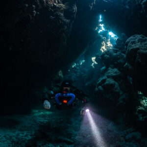 Rebreather diver beneath a glowing skylight, Saint John's Cave, Red Sea, Egypt