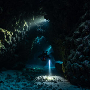 Rebreather diver in a side gallery of the cave with green walls, Saint John's Cave, Red Sea, Egypt