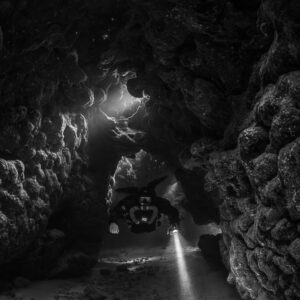 Rebreather diver in a side gallery, black and white, Saint John's Cave, Red Sea, Egypt