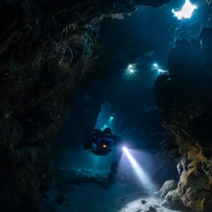Rebreather diver below scattered skylights, Saint John's Cave, Red Sea, Egypt