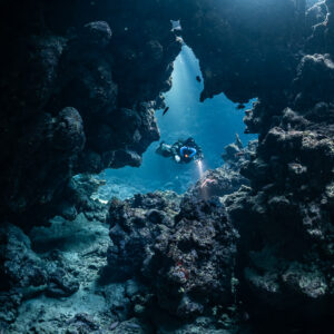 Rebreather diver in a cave window opening onto the blue, Sha'ab Claudio, Red Sea, Egypt