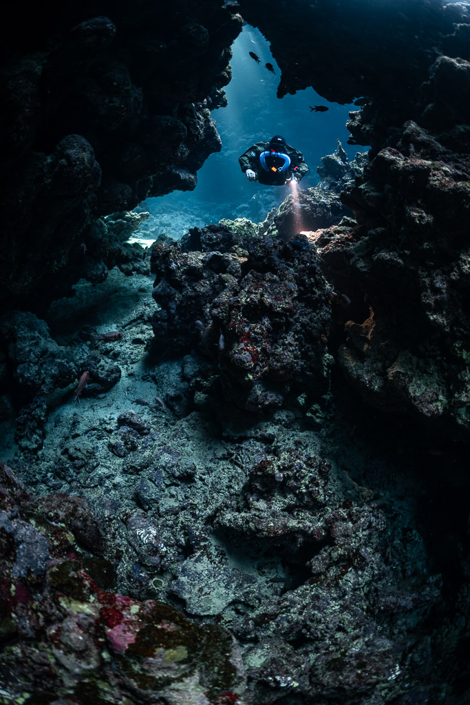 Rebreather diver high in a blue cave window, rubble below, Sha'ab Claudio, Red Sea, Egypt