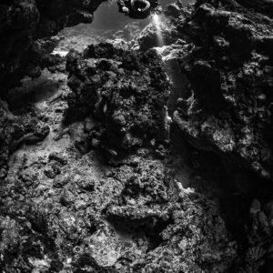 Rebreather diver high in a cave window, black and white, Sha'ab Claudio, Red Sea, Egypt