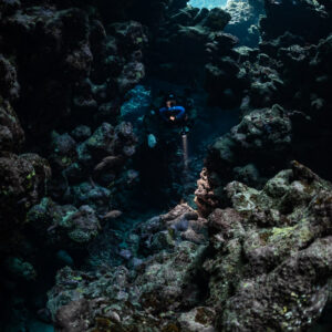 Rebreather diver deep in a dark cave passage, Sha'ab Claudio, Red Sea, Egypt