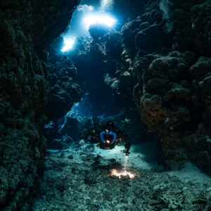 Rebreather diver far below twin skylights, Sha'ab Claudio, Red Sea, Egypt