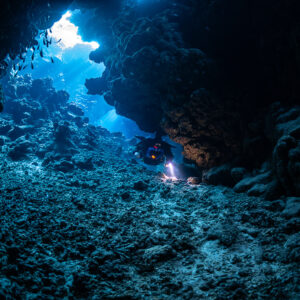 Rebreather diver at the far end of a wide blue cave mouth, Sha'ab Claudio, Red Sea, Egypt