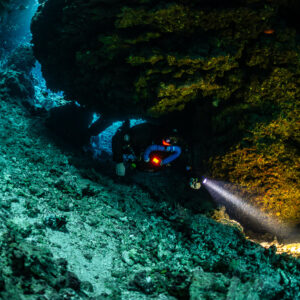Rebreather diver close-up lighting the golden cave wall, Sha'ab Claudio, Red Sea, Egypt