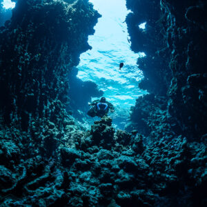 Rebreather diver in a canyon opening to the sunlit surface, Sha'ab Claudio, Red Sea, Egypt
