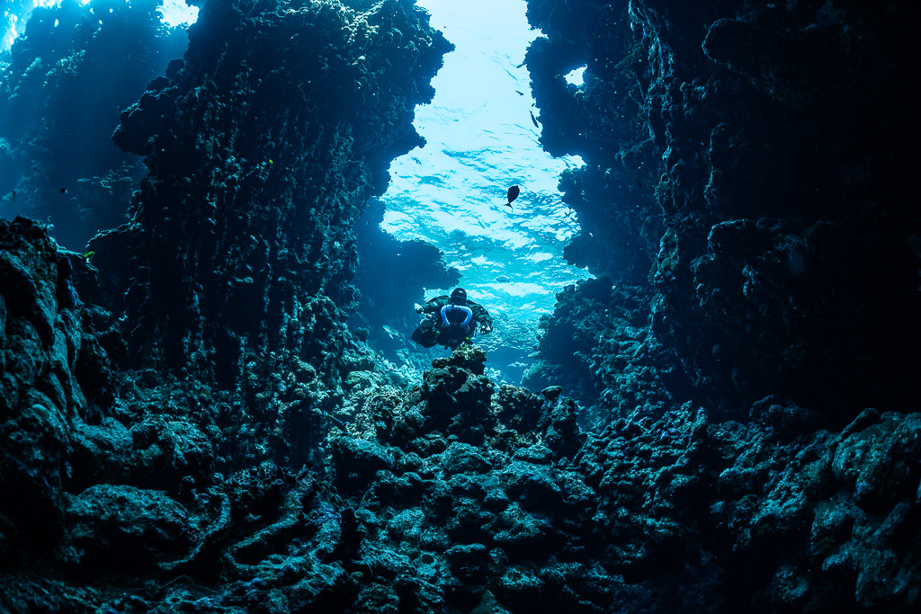 Rebreather diver in a canyon opening to the sunlit surface, Sha'ab Claudio, Red Sea, Egypt
