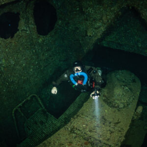 Rebreather diver inside the Numidia wreck with torch, Big Brother, Red Sea, Egypt