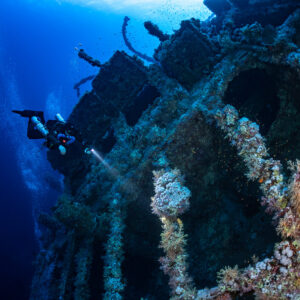 Rebreather diver lighting the coral-encrusted wheels of the Numidia wreck, Big Brother, Red Sea, Egypt