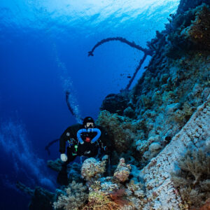 Rebreather diver beside coral-encrusted wheel of the Numidia wreck, Big Brother, Red Sea, Egypt