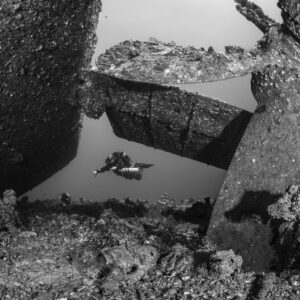 Black-and-white view of a diver beyond a wreck propeller and rudder, Red Sea, Egypt
