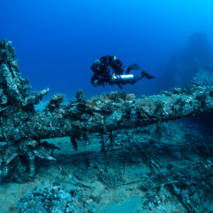 Rebreather diver gliding above an overgrown propeller shaft on a wreck, Red Sea, Egypt