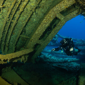 Rebreather diver framed by the rusty arch of a wreck hold, Red Sea, Egypt