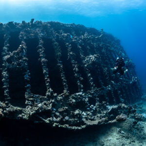Rebreather diver beside the exposed ribs of a wreck hull, Red Sea, Egypt