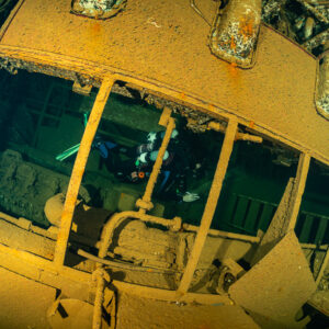Rebreather diver seen through rusty railings inside a wreck, Red Sea, Egypt
