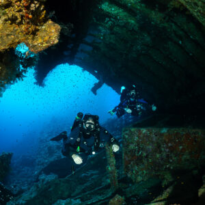Rebreather diver in a wreck opening against blue water, vertical, Red Sea, Egypt