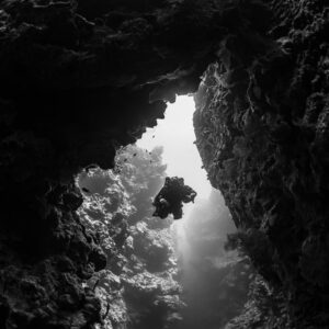 Silhouette d’un plongeur encadré par une arche rocheuse, en noir et blanc, vertical rapproché, mer Rouge, Égypte
