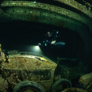 Rebreather diver lighting a truck cab in a dark cargo hold, Thistlegorm wreck, Red Sea, Egypt