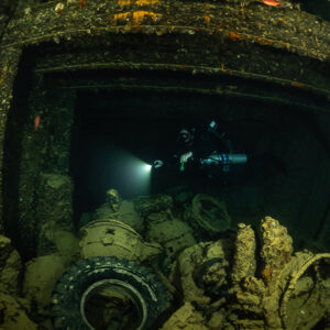 Rebreather diver above tyres and vehicle parts in a cargo hold, Thistlegorm wreck, Red Sea, Egypt
