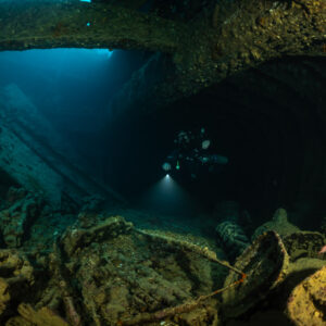 Rebreather diver in a hold with blue light from a hatch, Thistlegorm wreck, Red Sea, Egypt