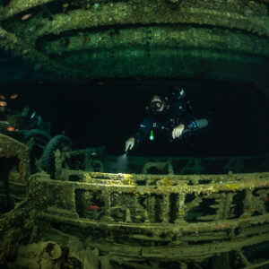 Rebreather diver behind the side rail of a truck in a hold, Thistlegorm wreck, Red Sea, Egypt