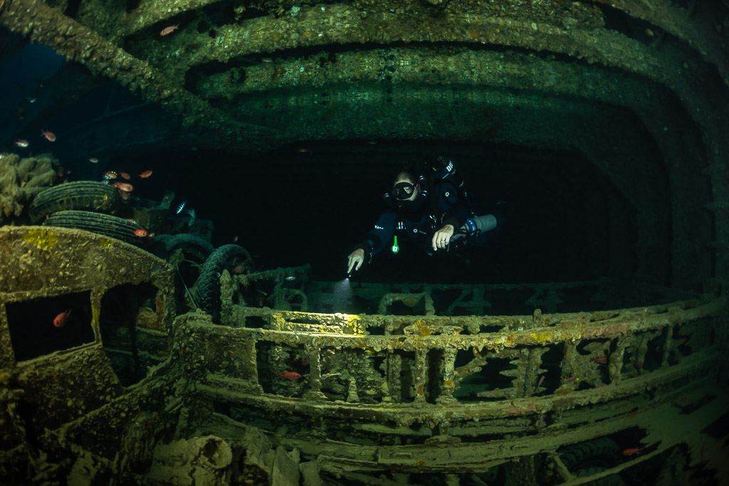 Rebreather diver behind the side rail of a truck in a hold, Thistlegorm wreck, Red Sea, Egypt