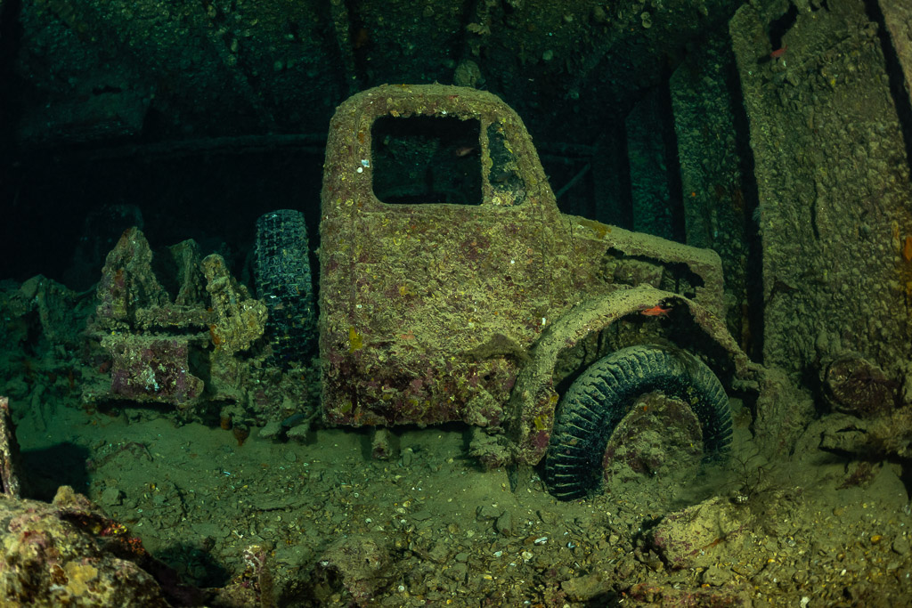Encrusted truck cab standing in a dark cargo hold, Thistlegorm wreck, Red Sea, Egypt
