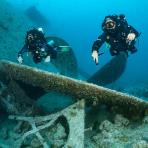 Two rebreather divers above a fallen plate near a wreck propeller, Thistlegorm wreck, Red Sea, Egypt